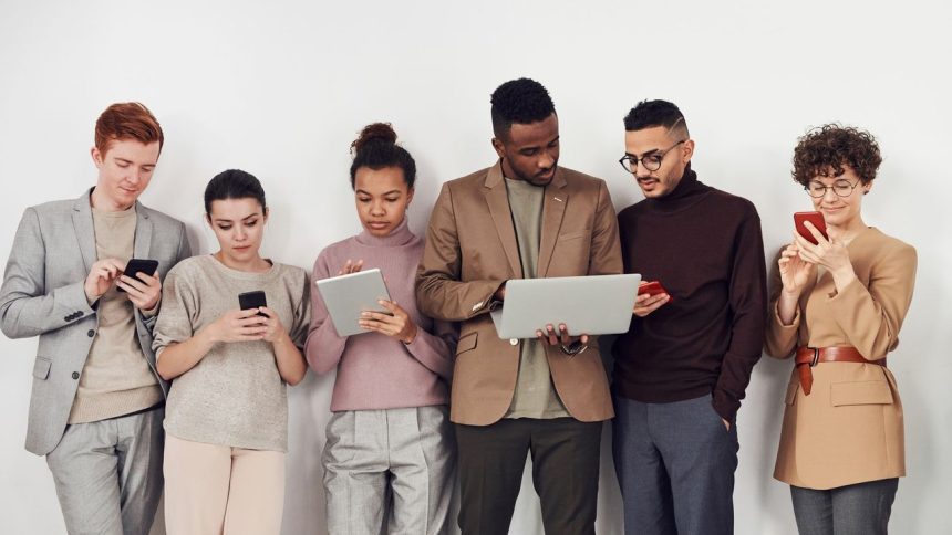 Grupo diverso de jovens usando dispositivos móveis em um ambiente interno.