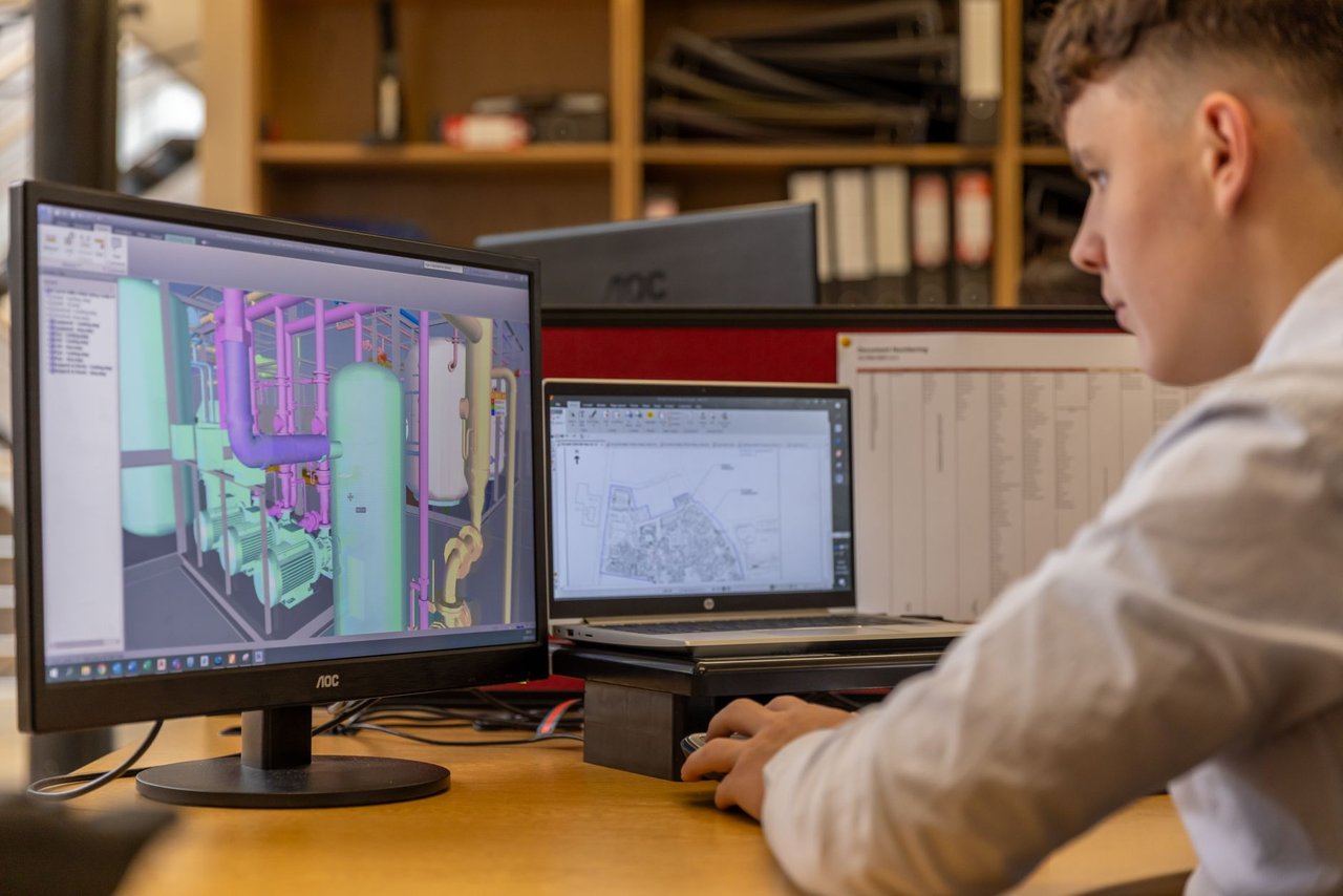 Engenheiro trabalha com software CAD em dois monitores em um escritório.