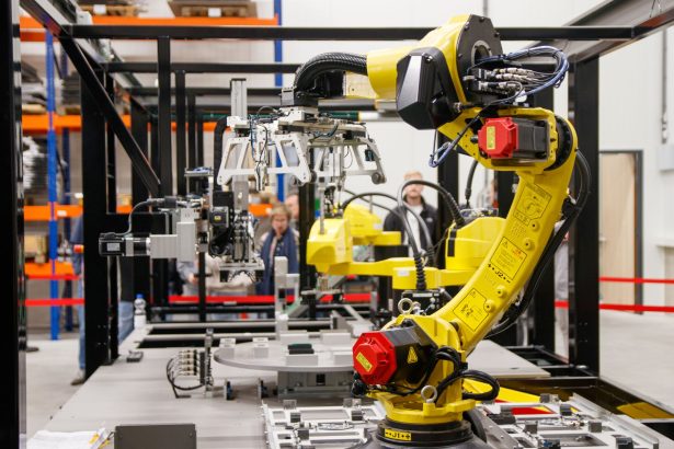 Braço robótico industrial amarelo em operação em uma instalação moderna de manufatura.