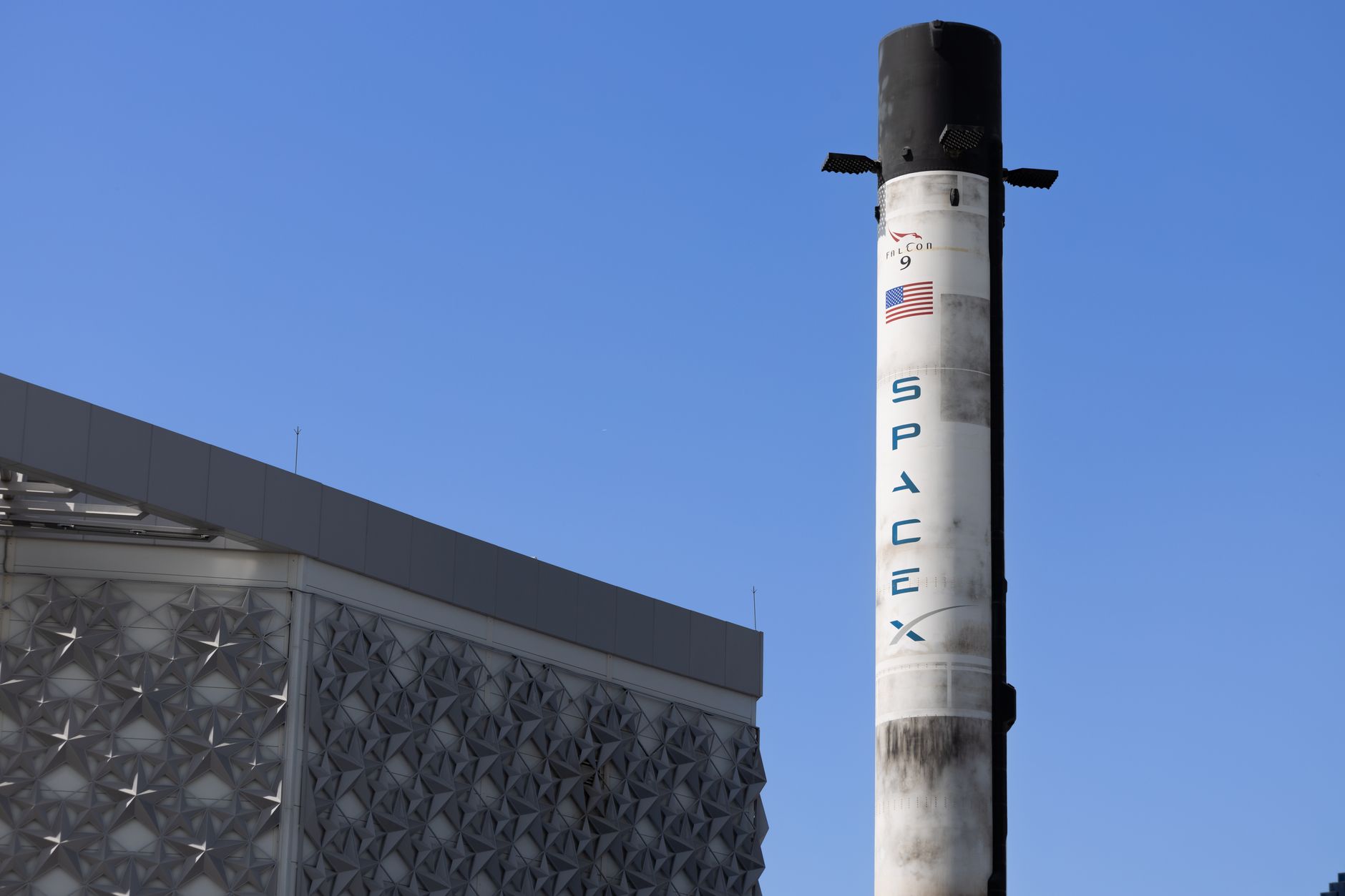 Foguete Falcon 9 da SpaceX exposto ao ar livre sob um céu azul.